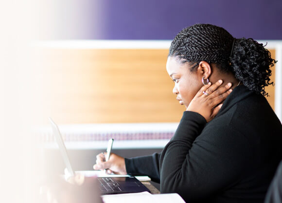 An adult student taking notes in front of a computer